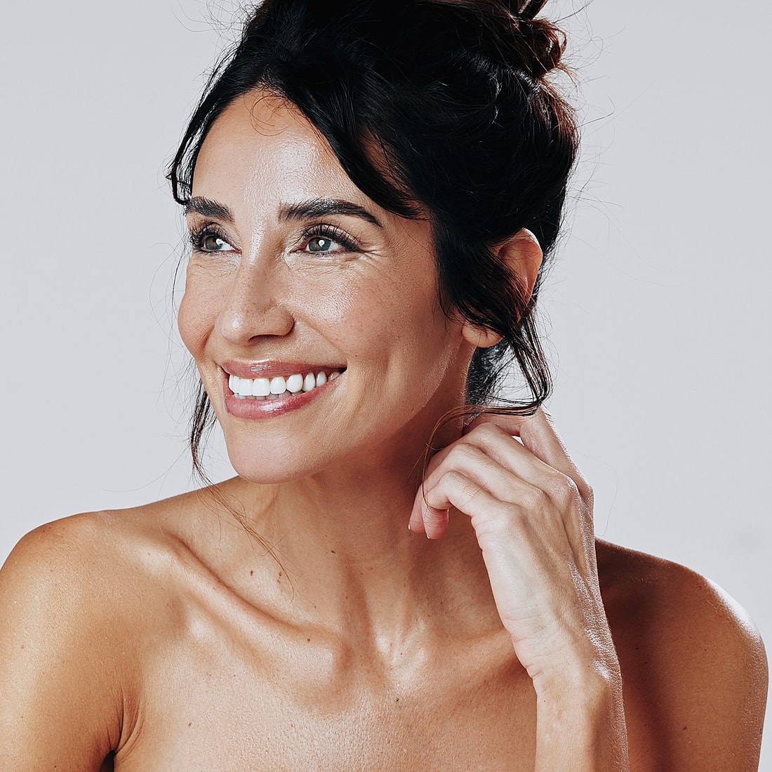 Smiling woman with natural makeup and relaxed pose.