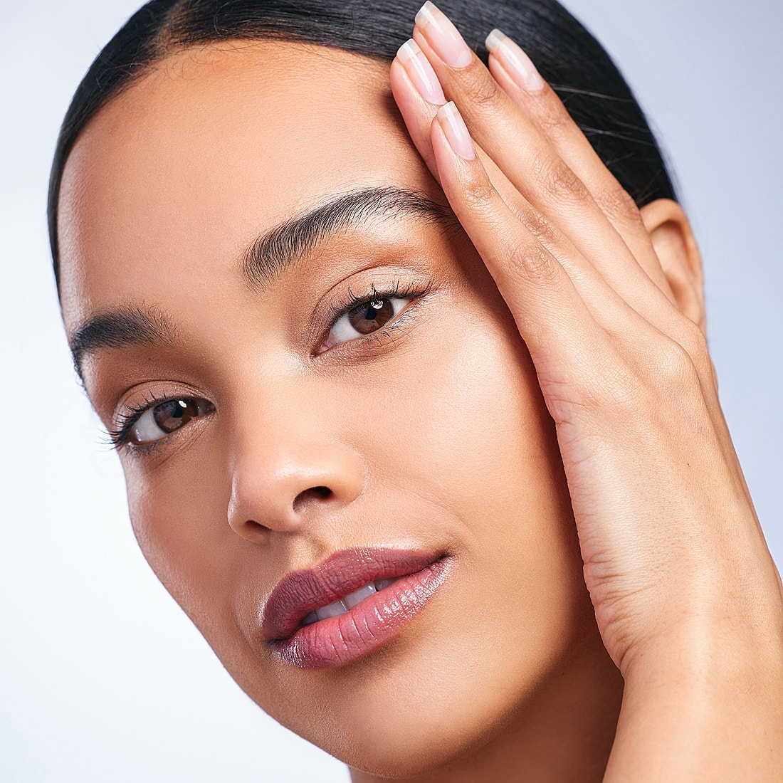 Close-up of a woman touching her face.