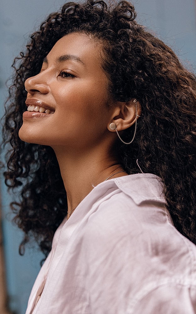 Profile of a woman with curly hair and earrings.