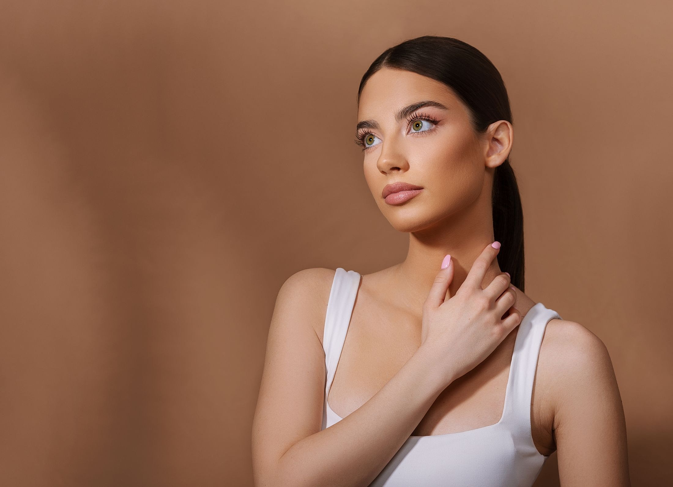 Woman with elegant makeup against brown background.