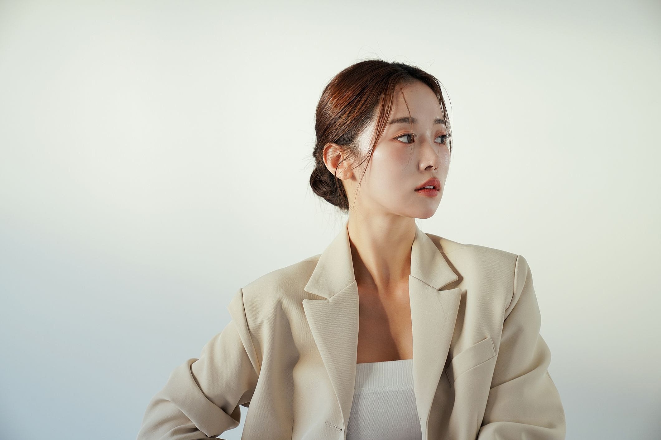 Woman in a blazer with neutral background.