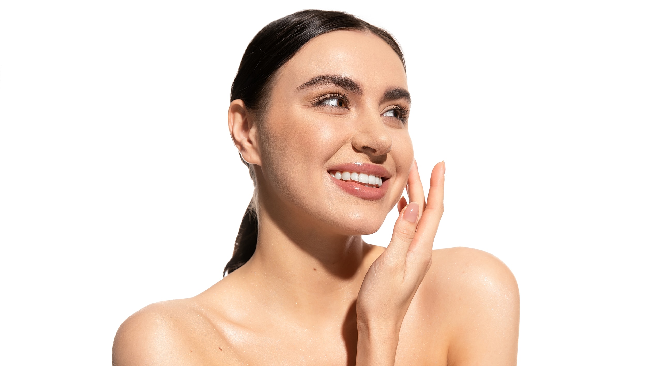 Smiling woman with glowing skin, hand on face.